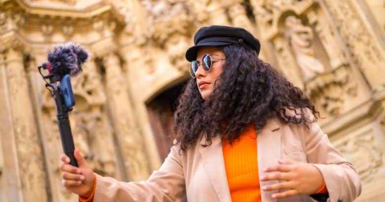 A travel influencer recording content with a handheld camera in front of an ornate historical building, showcasing the impact of travel content marketing and video marketing in engaging audiences.